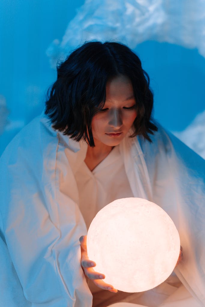 A conceptual image of a woman holding a glowing sphere, evoking dreams and fantasy under a blue night sky.