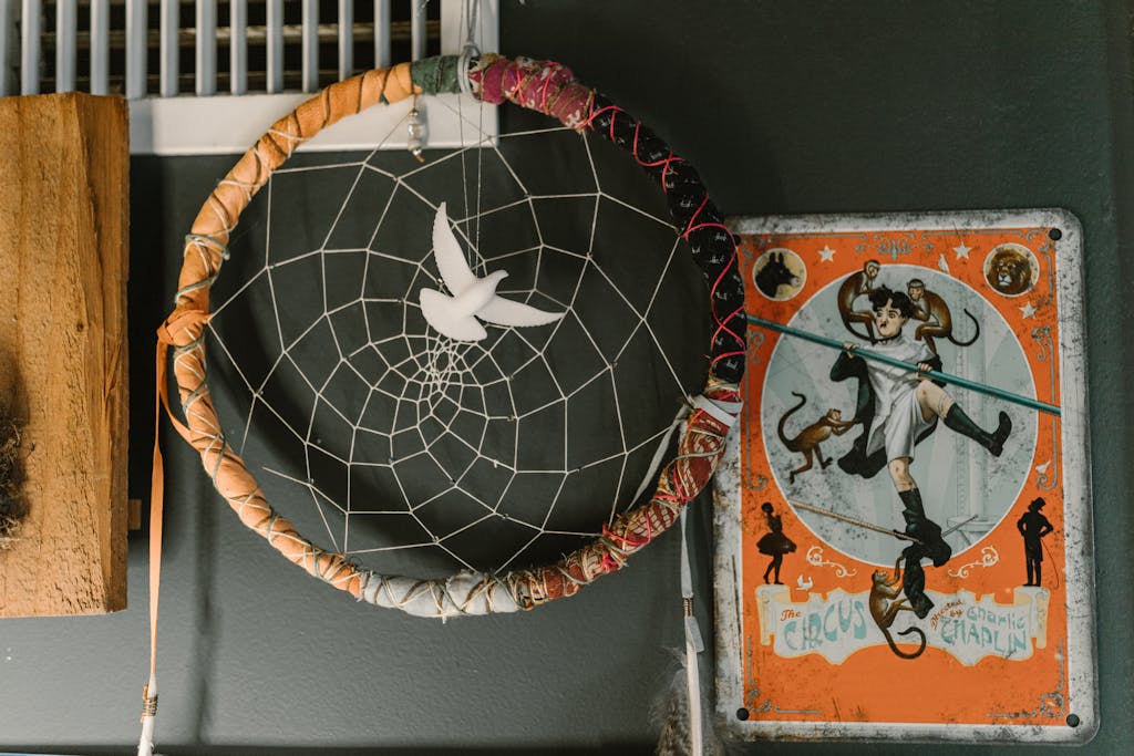 Close-up of dream catcher and vintage circus poster on a gray wall, featuring a unique decorative setup.