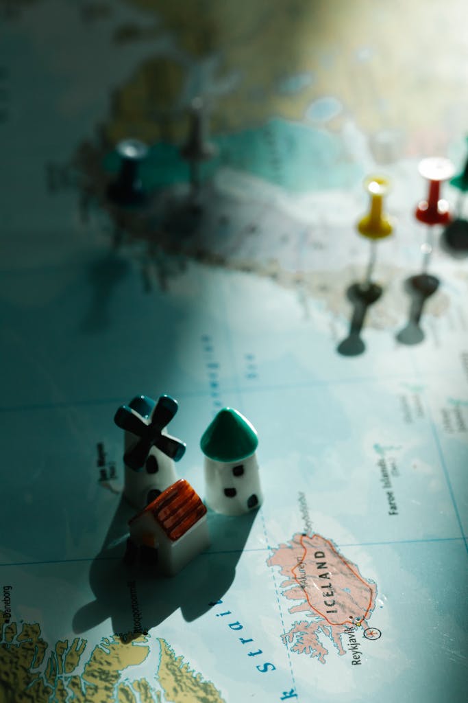 Miniature figurines on a map of Iceland with selective focus and pushpins.